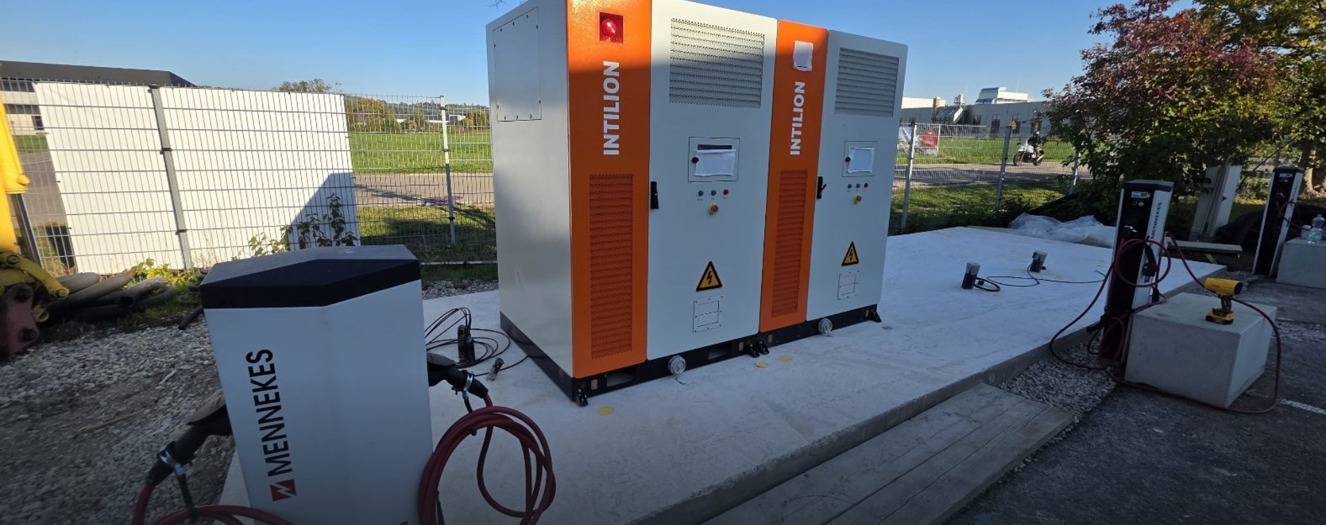 Gewerbespeicher mit zwei Batterieschränken und einer Ladesäule auf einem Betonfundament