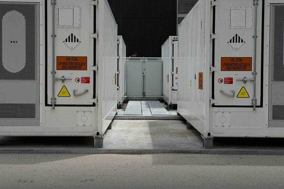 Gang zwischen zwei Batteriespeicher-Containern an einem Industriestandort