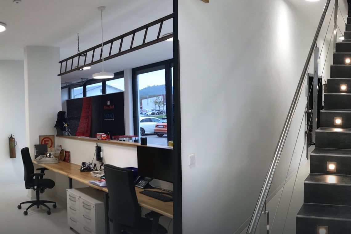 Büro mit Arbeitsplätzen und beleuchteter Treppe in einem Gewerbebau