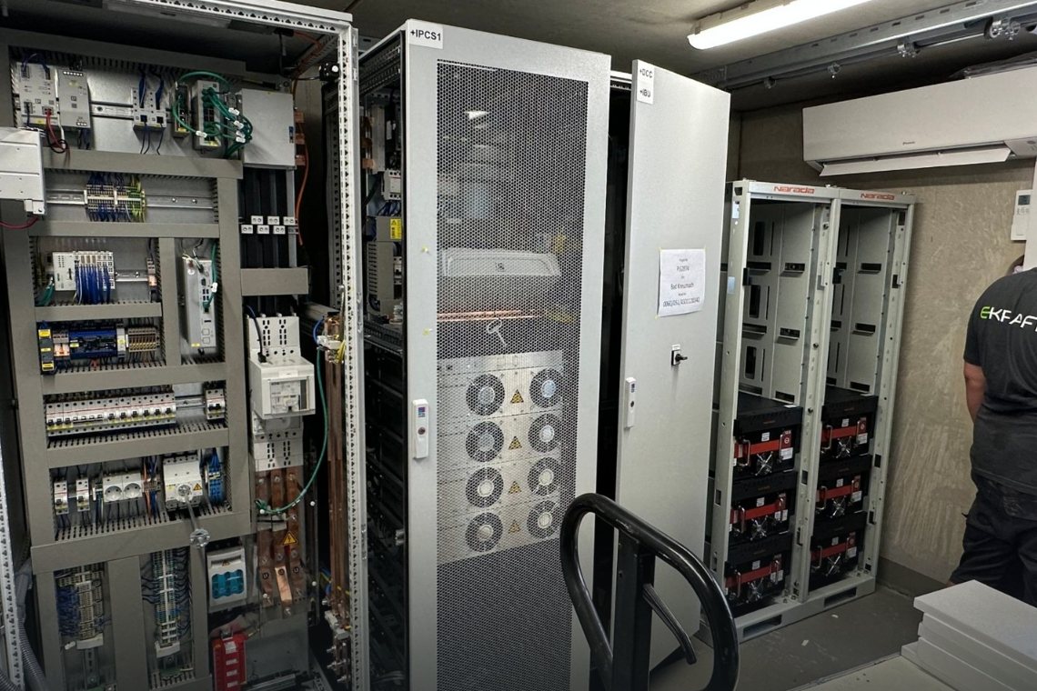 Speicherraum mit Schaltschrank, PCS und Batterie-Racks, rechts ein EKRAFT-Techniker