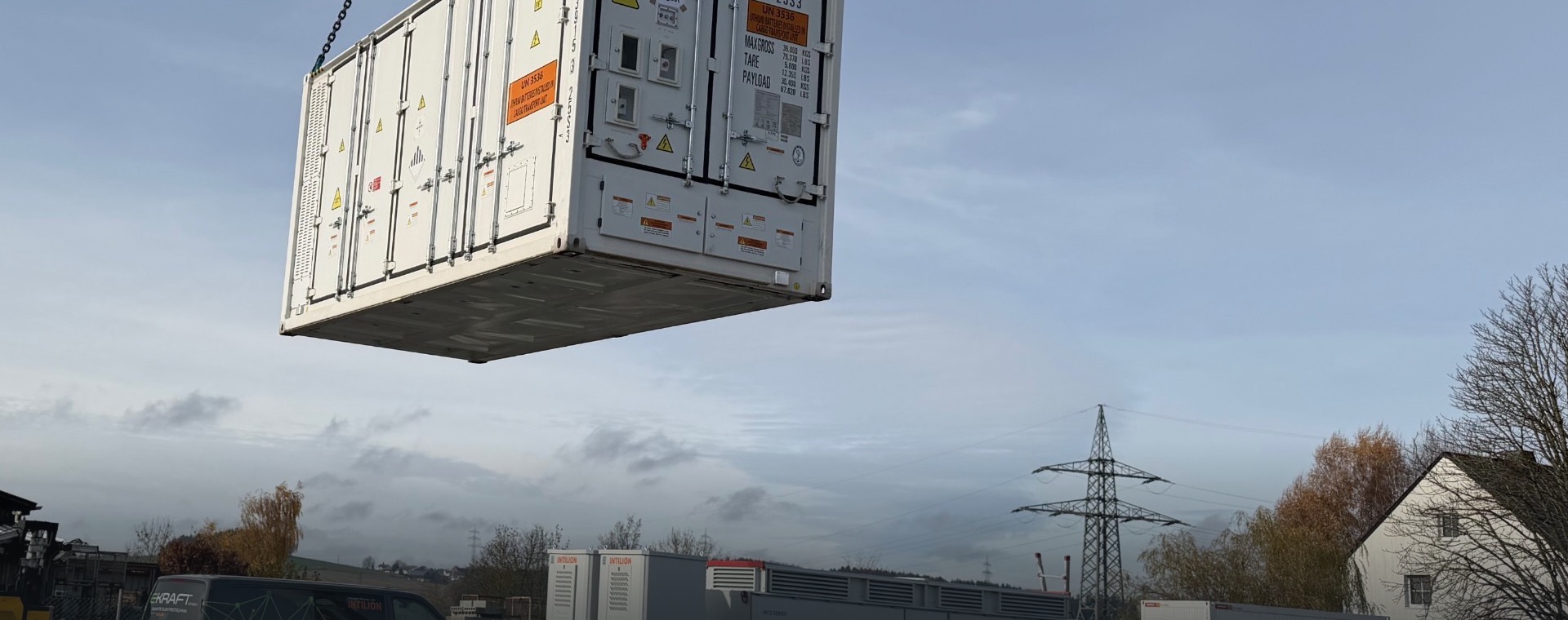 Kran hebt einen Batteriecontainer auf das Fundament eines Speicherparks