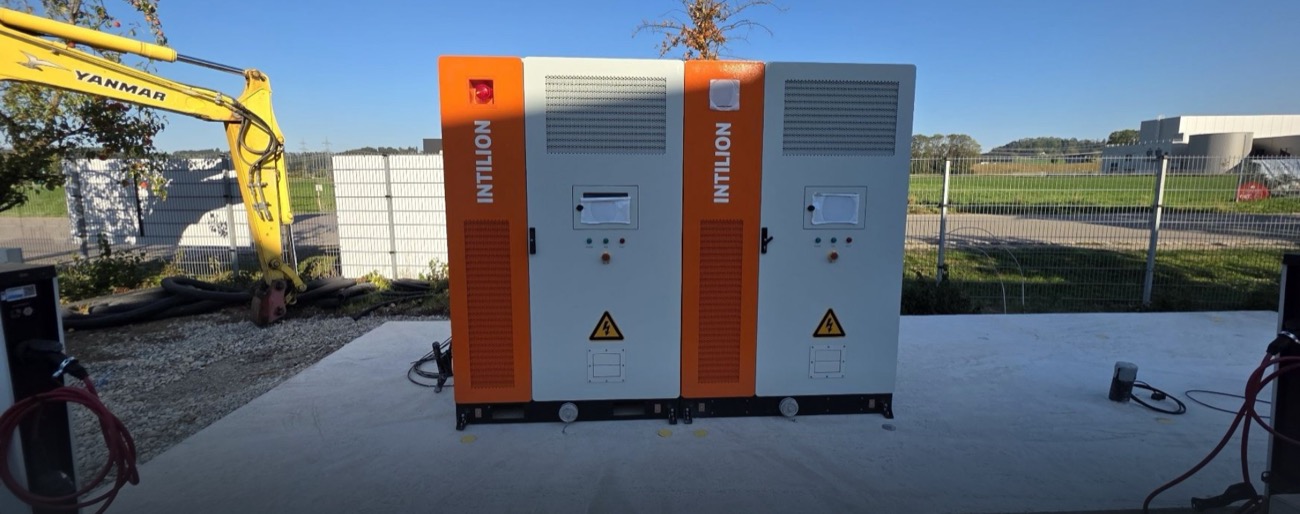 Gewerbespeicher mit zwei Batterieschränken bei der Inbetriebnahme, im Hintergrund ein Bagger